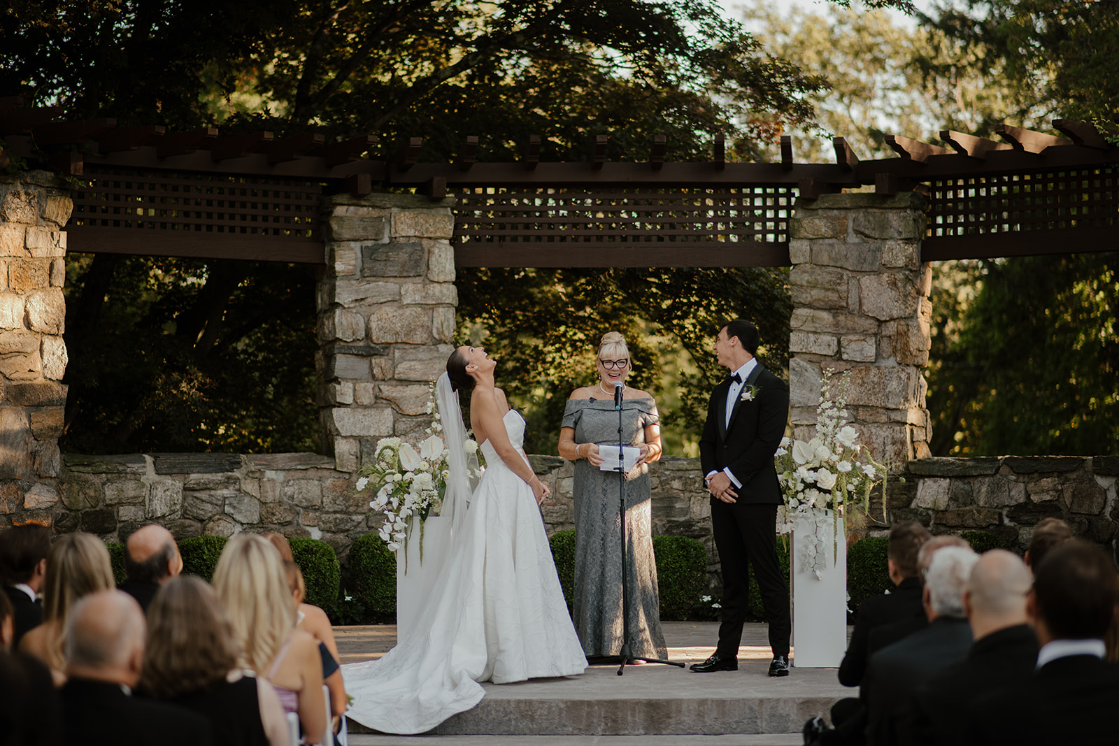 Bride laughing joyfully and throwing her head back during the ceremony at the stone altar.
